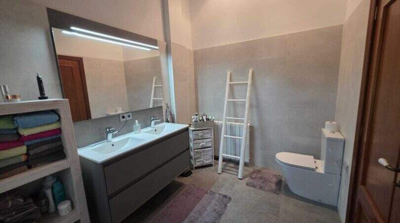 Modernes Badezimmer der Finca S'Illot mit Doppelwaschbecken, beleuchtetem Spiegel und WC