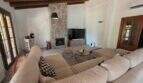 Wohnzimmer der Finca S'Illot mit Steinofen, Holzbalkendecke, großem Sofa und TV-Bereich