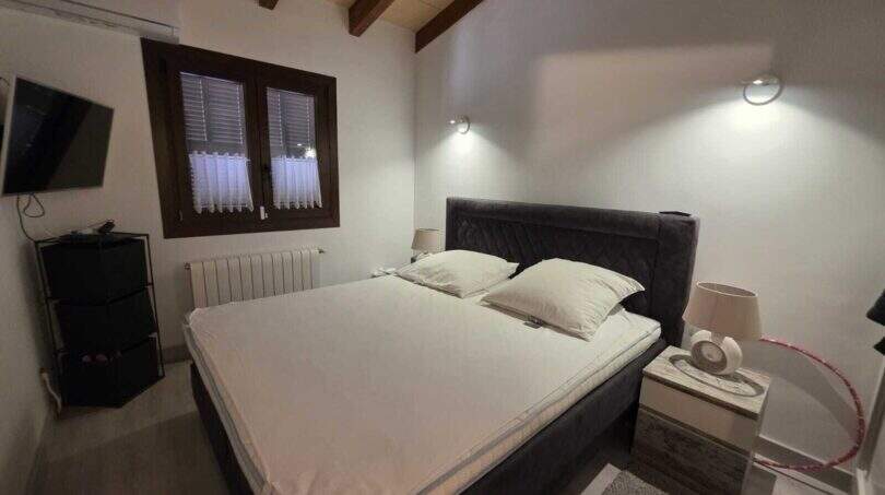 Schlafzimmer der Finca S'Illot mit Doppelbett, Holzbalkendecke, TV und Klimaanlage