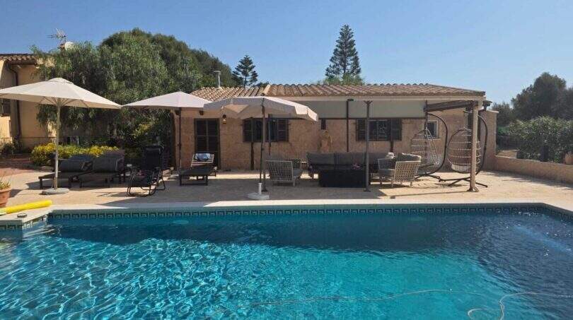 Finca S'Illot: Großer Außenpool mit Terrasse, Liegestühlen, Sonnenschirmen und Schaukelstühlen vor dem Steinhaus.