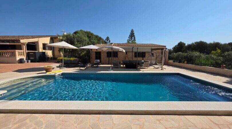 Finca S'Illot: Rechteckiger Pool mit Natursteinumrandung, Sonnenschirme und Gästehaus im mediterranen Garten