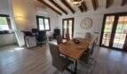 Heller Essbereich mit Holztisch, Balkendecke und Arbeitsbereich in mallorquinischer Finca in S'Illot