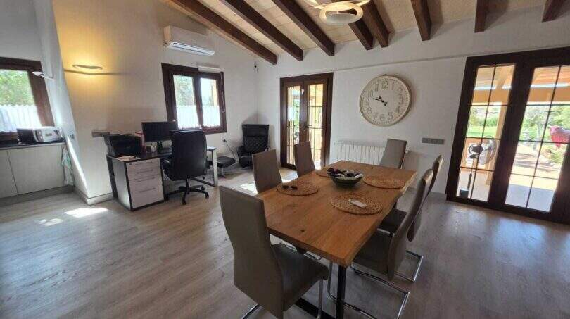 Heller Essbereich mit Holztisch, Balkendecke und Arbeitsbereich in mallorquinischer Finca in S'Illot
