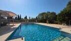 Großer Außenpool mit blauem Wasser, Sonnenschirm und mediterranem Garten der Finca in S'Illot