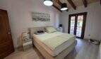 Helles Schlafzimmer der Finca S'Illot mit Doppelbett, Holzbalkendecke und Terrassenzugang
