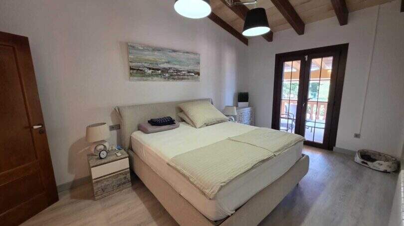 Helles Schlafzimmer der Finca S'Illot mit Doppelbett, Holzbalkendecke und Terrassenzugang
