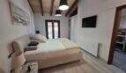 Helles Schlafzimmer der Finca S'Illot mit Holzbalkendecke, Doppelbett, TV und Balkonzugang