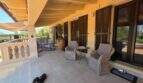 Überdachte Terrasse der Finca S'Illot mit Korbmöbeln, Holzläden und Hund auf Fliesenboden