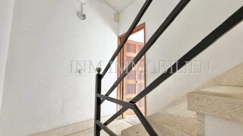 Staircase with black metal railing, marble stairs and wooden door in renovation apartment, Playa de Palma