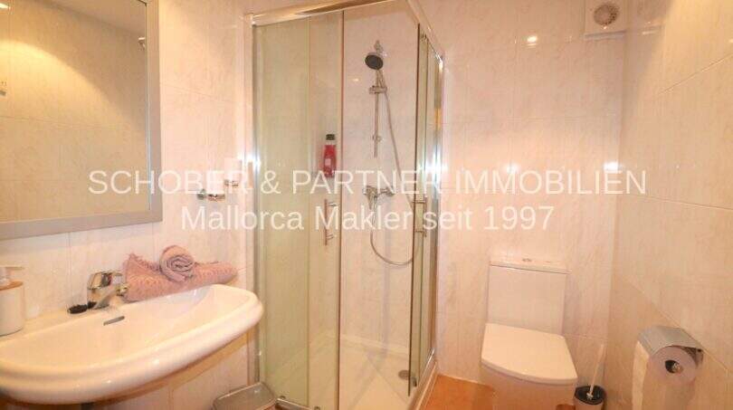 Helles Badezimmer der Poolwohnung in Sa Coma mit Glasdusche, WC und Waschbecken in modernem Design.
