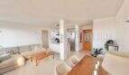 Heller Wohn-Essbereich mit Sofa, Holztisch, offener Küche und Terrakottaboden in Palmanova-Wohnung.