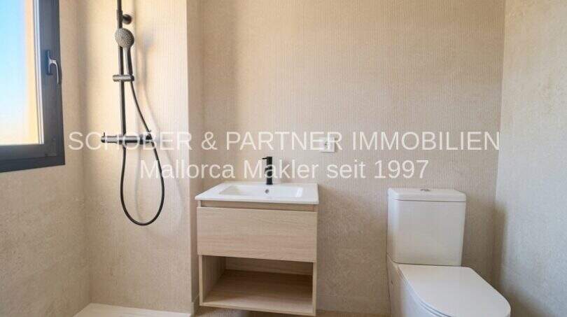 Baño moderno del apartamento esquinero de nueva construcción en Cala Millor con ducha, lavabo e inodoro en colores claros.