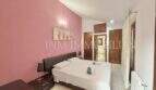 Schlafzimmer mit Doppelbett, rosa Akzentwand und Holztüren im Ferienhaus Muro