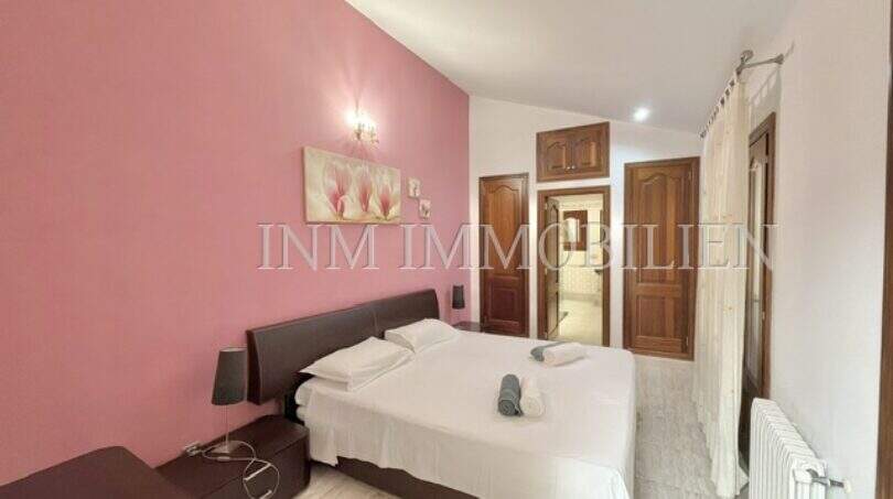 Schlafzimmer mit Doppelbett, rosa Akzentwand und Holztüren im Ferienhaus Muro