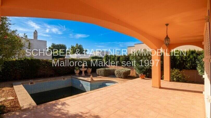Überdachte Terrasse mit Pool und gepflegtem Garten eines Einfamilienhauses in Sa Coma, nahe Strand.