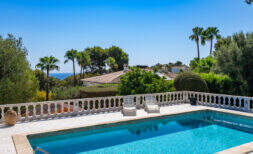 Piscina privada con balaustrada blanca, vista al mar y palmeras en Villa Cala Murada