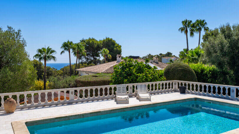 Private pool with white balustrade, sea view and palm trees in Villa Cala Murada
