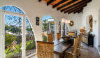Mediterranean dining room of the sea view villa in Cala Murada with wooden beam ceiling, wicker chairs and wrought iron window.
