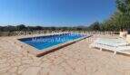 Outdoor area of the finca in Son Carrió with rectangular pool, natural stone terrace and sun loungers under blue sky.