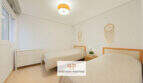 Helles Schlafzimmer der Erdgeschosswohnung Cala Antena mit zwei Einzelbetten, weißen Wänden und Traumfängern.