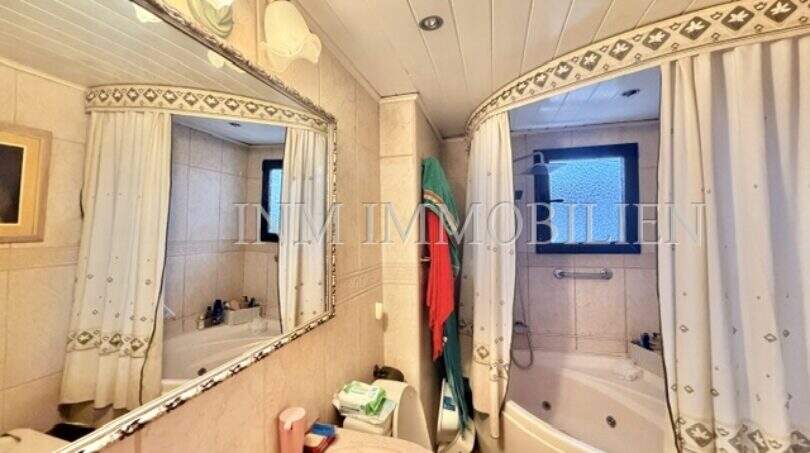 Badezimmer der Wohnung in Palma-City mit Whirlpool-Badewanne, Dusche, Waschbecken und großem Spiegel.