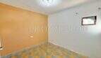 Empty room with orange accent wall, checkerboard floor and small window, apartment needing renovation Palma