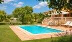 Finca Mallorca: Rechteckiger Außenpool mit Sandsteintefrasse, Liegestühlen und mediterranem Garten