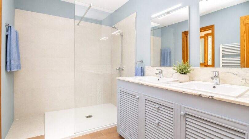 Helles Badezimmer der Finca mit Doppelwaschbecken, Marmor-Waschtisch und ebenerdiger Glasdusche