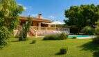 Finca Palma de Mallorca: Steinvilla mit Balustrade, Pool, Liegestühlen und gepflegtem Garten mit Bäumen.