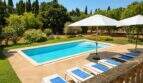 Finca Mallorca: Rechteckiger Außenpool mit Liegestühlen, Sonnenschirmen und gepflegtem Garten mit Zypressen