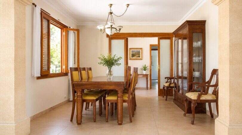 Elegantes Esszimmer der Mallorca-Finca mit Holztisch, Vitrine und Natursteinboden
