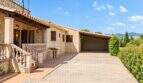 Finca Palma: Steinhaus-Außenansicht mit Carport, Terrasse, Balustrade und Bergblick bei blauem Himmel