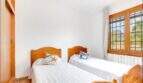 Helles Schlafzimmer der Finca mit zwei Einzelbetten aus Holz, weißen Wänden und Fenster mit Bergblick.