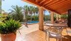 Überdachte Terrasse der Finca mit Holzdecke, Sitzbereich und Pool umgeben von Palmen in Palma de Mallorca