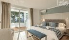 Dormitorio luminoso con cama doble, aire acondicionado y balcón con vista al verde en el hotel-apartamento Portocolom