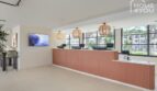 Área de recepción moderna del hotel-apartamento en Portocolom con mostrador, lámparas de ratán y vista a la piscina.