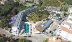 Vista aérea del apartahotel Portocolom: complejo moderno con piscina, palmeras, restaurante e instalaciones recreativas en ambiente mediterráneo.