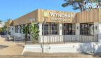 Vista exterior del Hotel Wyndham Portocolom con fachada moderna de madera, recepción y plantas tropicales, Mallorca