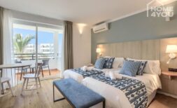 Helles Hotelzimmer mit zwei Betten, blauem Dekor, Klimaanlage und Balkon mit Meerblick in Portocolom