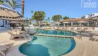 Piscina con área infantil, tumbonas y palmeras del apartahotel en Portocolom
