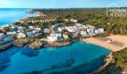 Vista aérea del apartahotel Portocolom: complejo con piscina, directamente en el mar turquesa, playa de arena, bosque de pinos