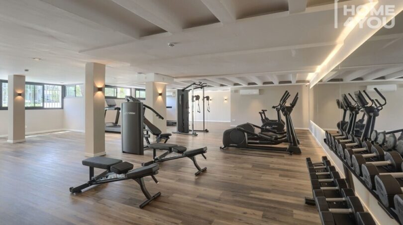 Gimnasio moderno con máquinas de cardio, mancuernas y estación de fuerza en el complejo apartahotel en Portocolom