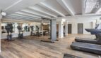 Centro de fitness moderno con cintas de correr, bicicletas estáticas y máquinas elípticas, suelo de madera, pared espejo en el apartahotel Portocolom