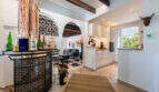 Open living and kitchen area of the sea view villa in Cala Murada with bar, barrel vault and modern white kitchen.