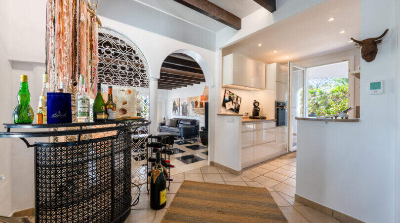 Open living and kitchen area of the sea view villa in Cala Murada with bar, barrel vault and modern white kitchen.