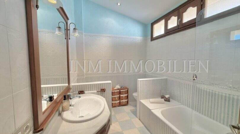 Helles Badezimmer mit Badewanne, Waschtisch und blauer Decke im Ferienhaus in Muro, Mallorca.