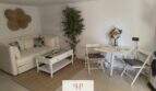 Helles Wohnzimmer mit weißem Sofa, Glascouchtisch und Essbereich im Ferienhaus nahe Strand Porto Cristo Novo