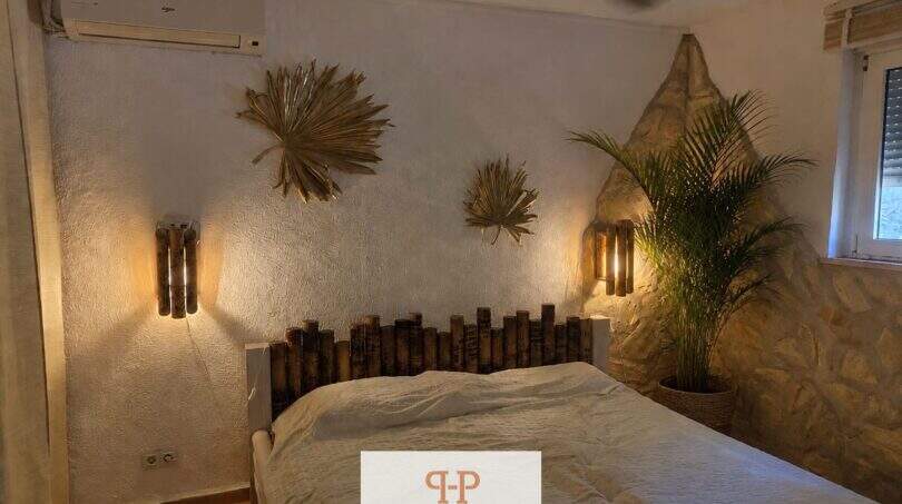 Schlafzimmer mit Bambus-Wanddeko, Steinwand, Palme, Bambus-Wandleuchten und Klimaanlage, Strandhaus Porto Cristo Novo