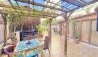 Überdachte Terrasse mit Holzpergola, Esstisch, Pflanzen und Loungebereich der Wohnung in Palma-City.