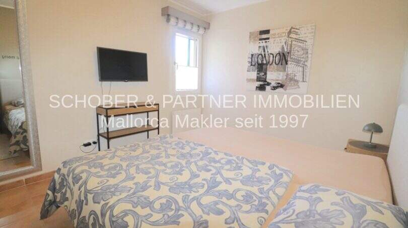Dormitorio luminoso del apartamento de 4 habitaciones en Cala Millor con cama doble, TV y cuadro decorativo de Londres en la pared.